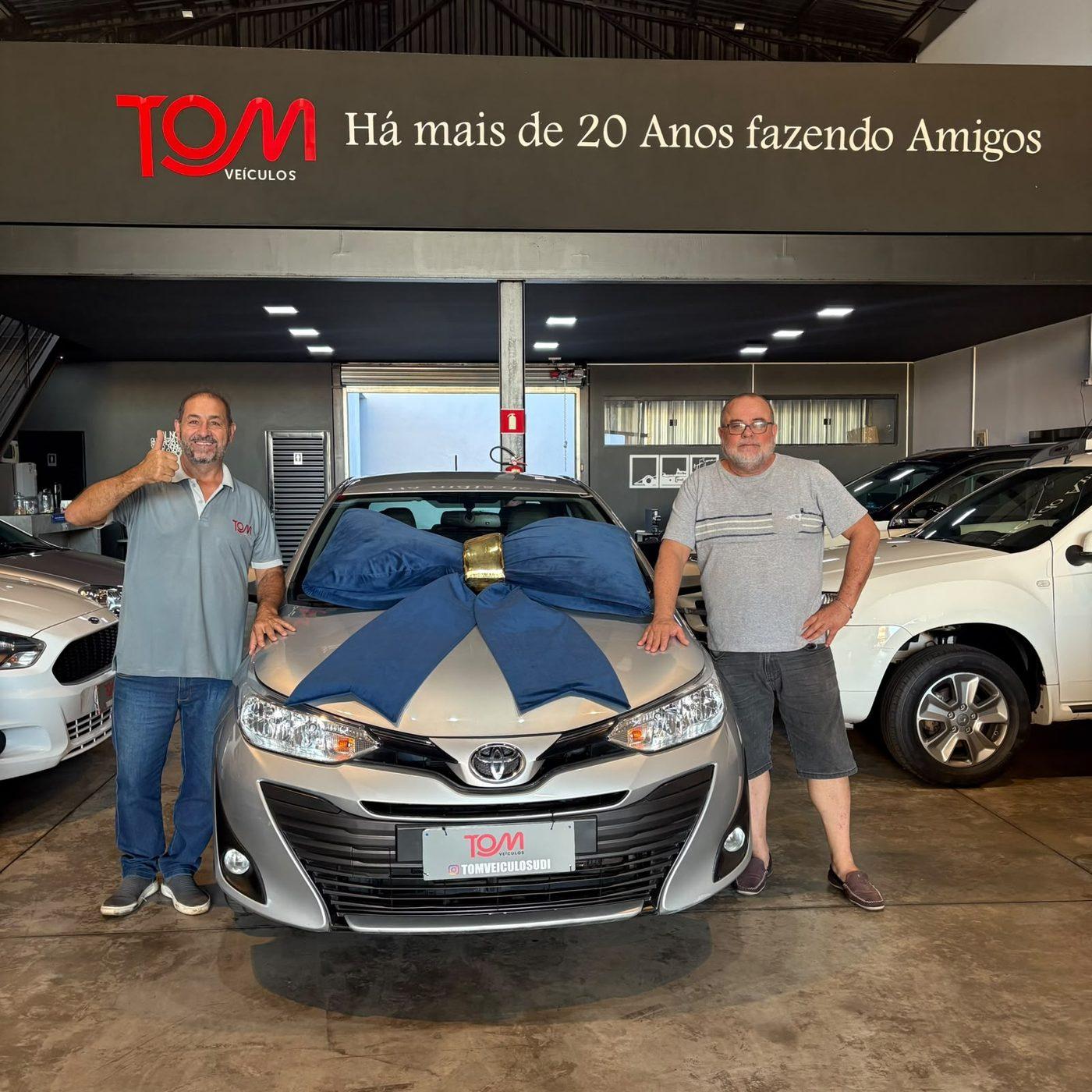 Cliente satisfeito posando com o veículo recém-entregue na Tom Veículos.